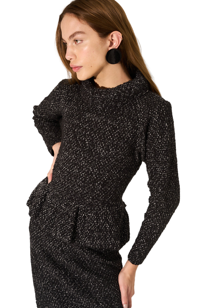 Woman wearing a black textured outfit against a neutral background