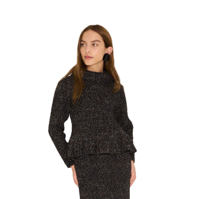 Woman wearing a black textured sweater and pants on a beige background