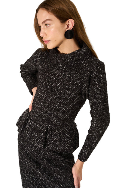 Woman wearing a black textured outfit against a neutral background