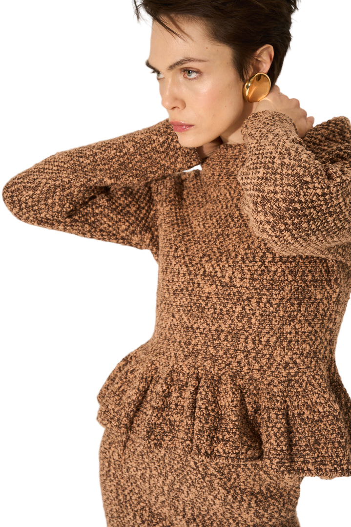 Woman wearing a brown textured dress against a plain background