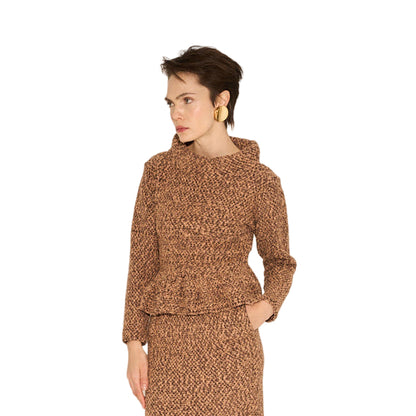 Woman wearing a brown patterned outfit with knee-high boots on a beige background