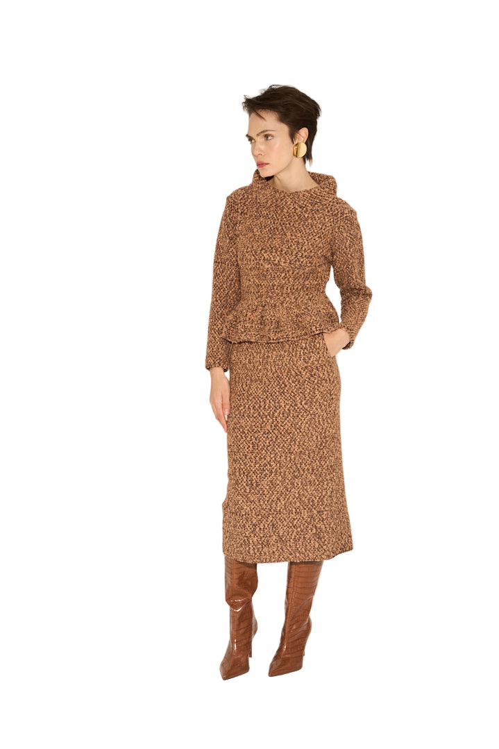 Woman wearing a brown patterned outfit with knee-high boots on a beige background