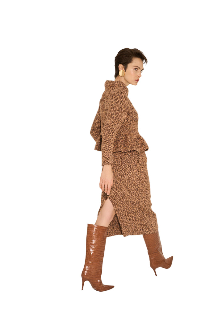 Woman wearing a brown knit outfit with knee-high boots on a plain background